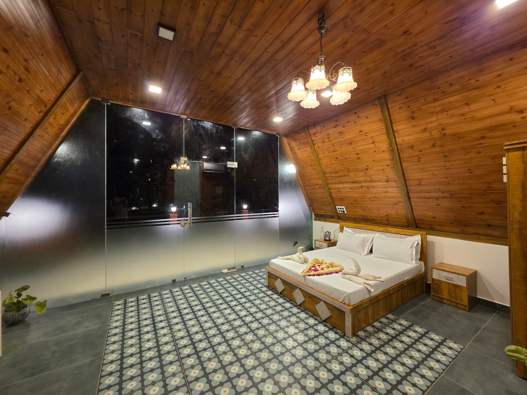 A-frame cottage bedroom with glass wall and chandelier