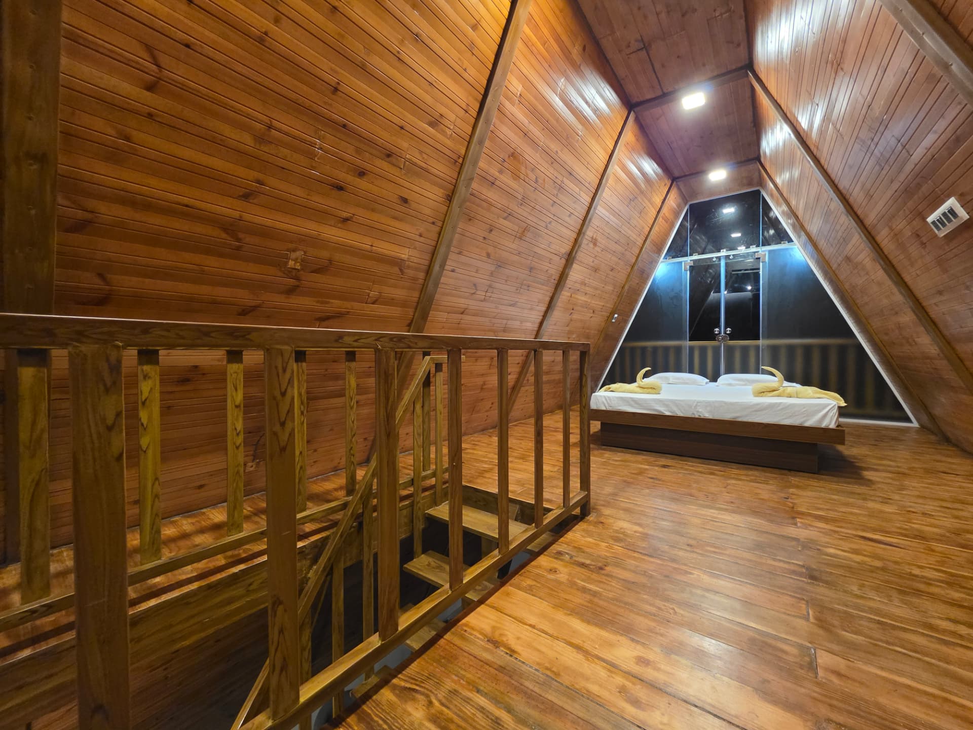 Wooden stargazer attic with king bed and staircase inside the A-Frame cottage