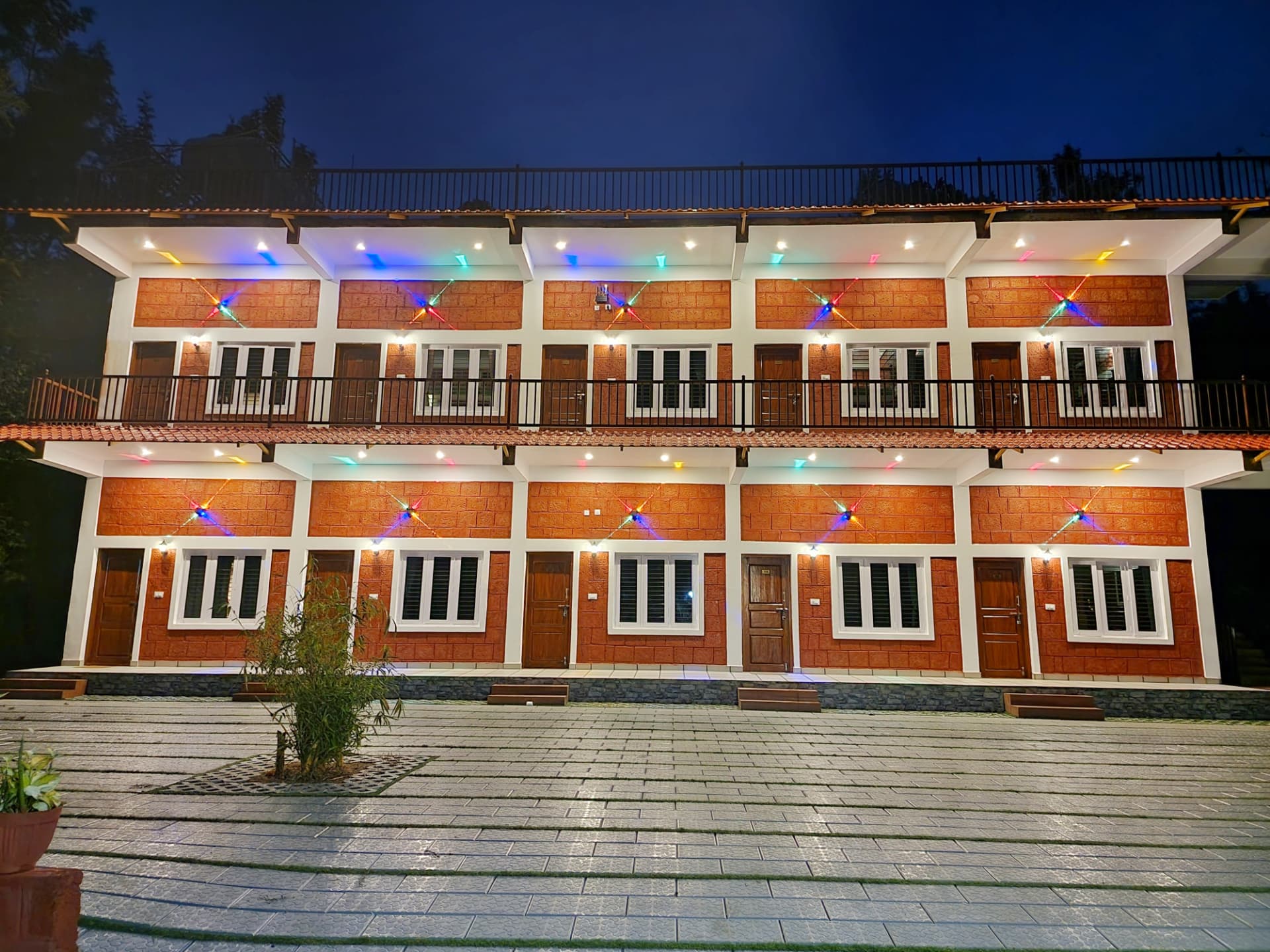 Stone Age Rooms block lit with colourful lights at dusk in Coorg