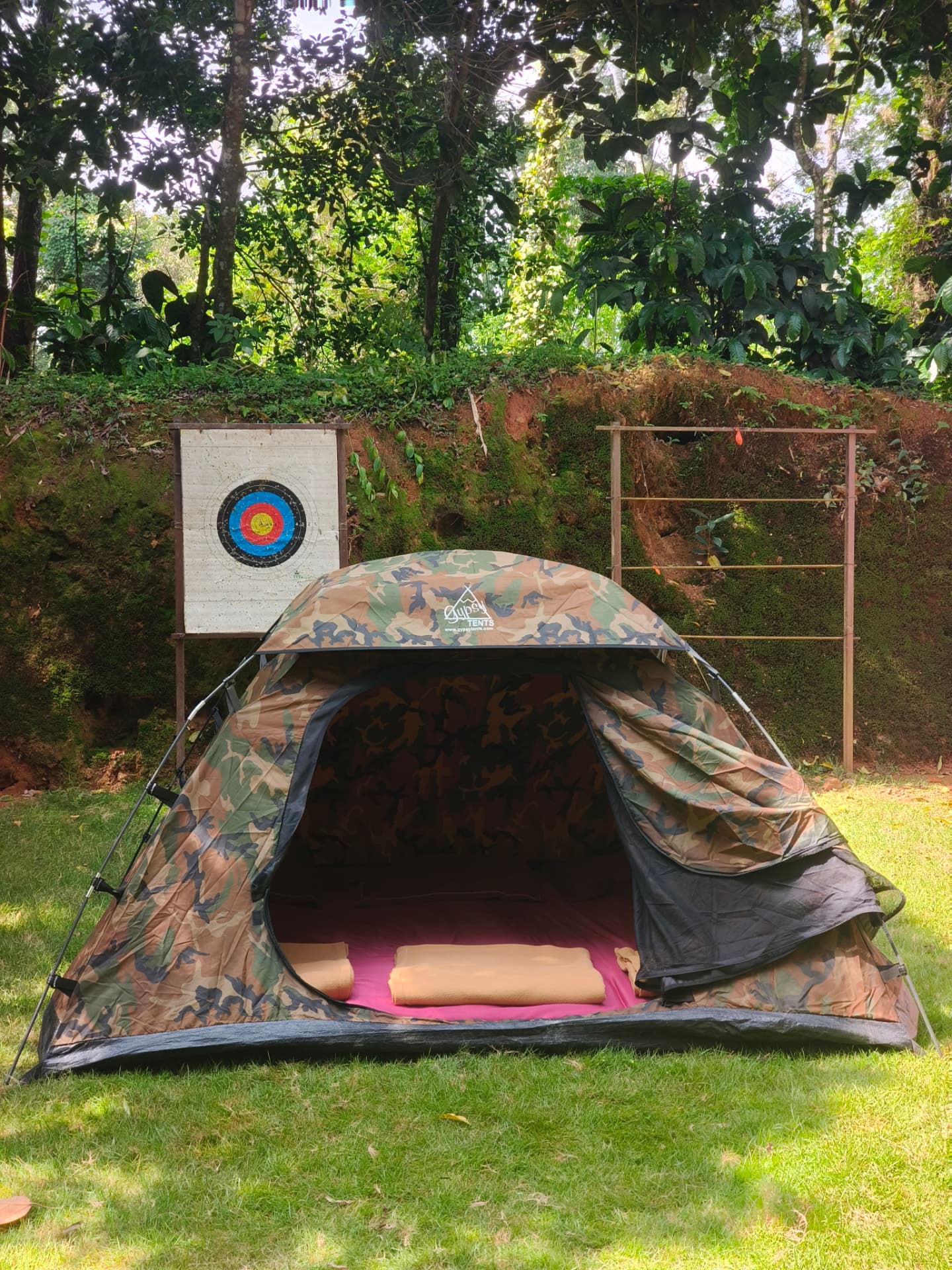 Open tent showing bedding, surrounded by greenery at Evergreen County